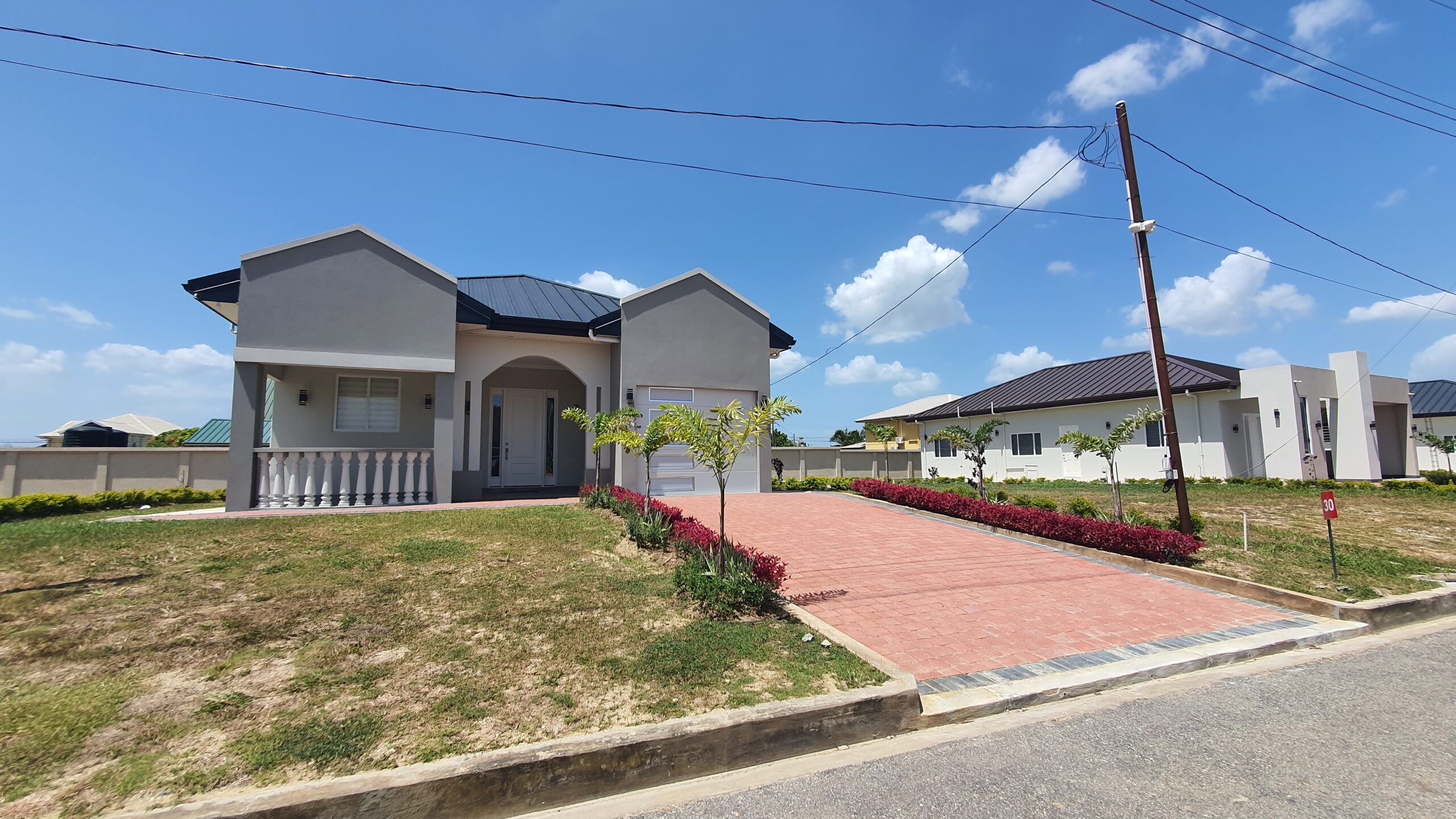 Modern Freeport home with red brick driveway and landscaping.