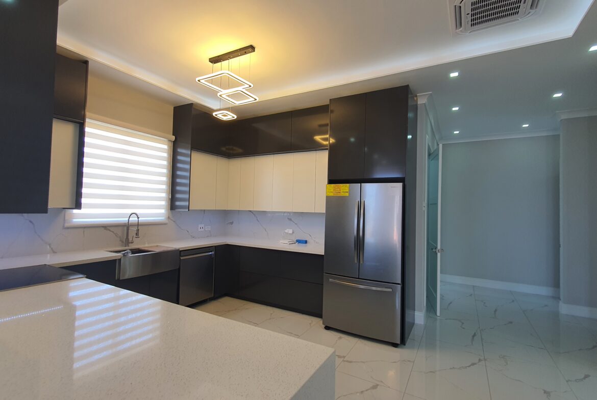 Modern kitchen with white cabinets, stainless steel appliances, and breakfast bar in a Freeport home.