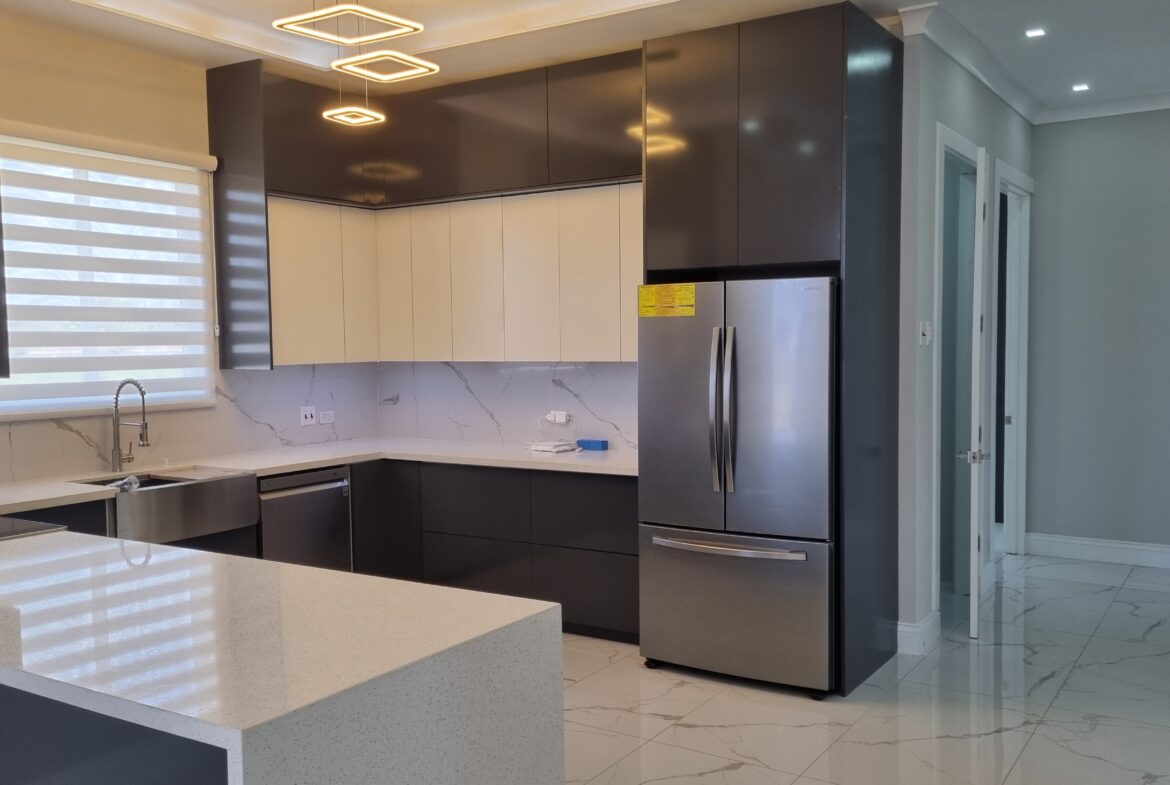 Modern kitchen with white and dark wood cabinets, stainless steel appliances, and breakfast bar in a Freeport home.