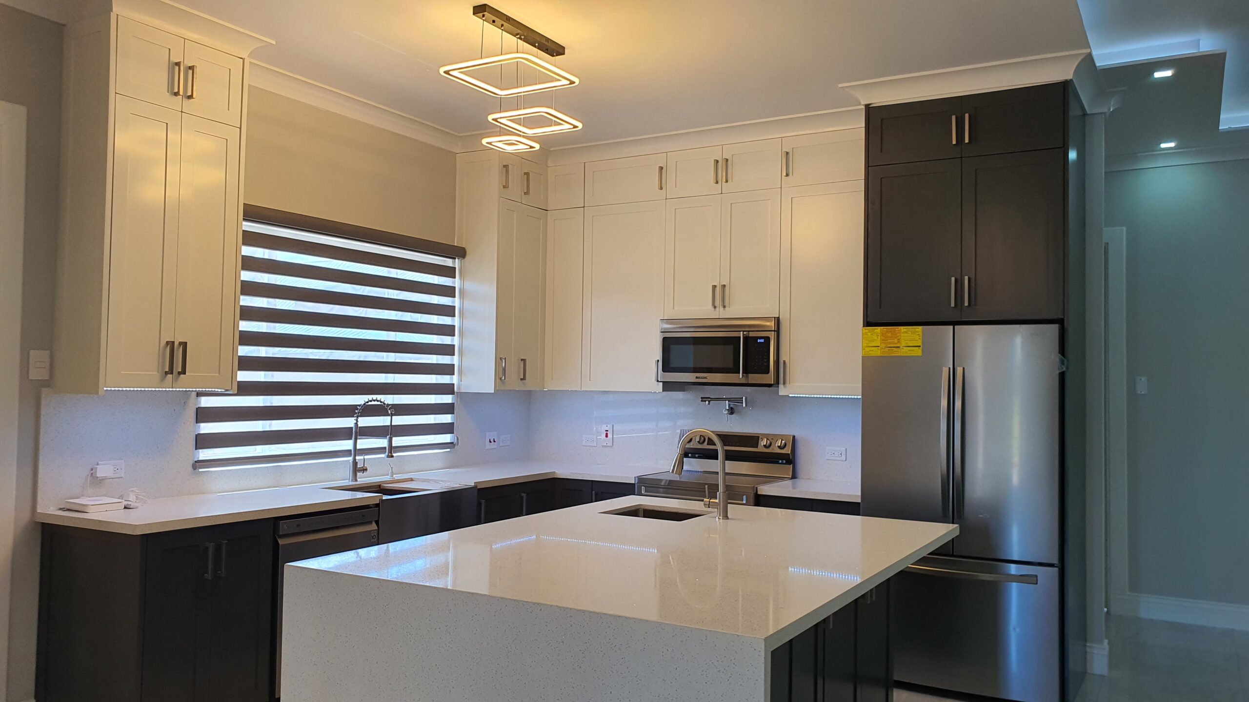 Modern kitchen with stainless steel appliances, island counter with built-in sink, and dishwasher in a Freeport home.