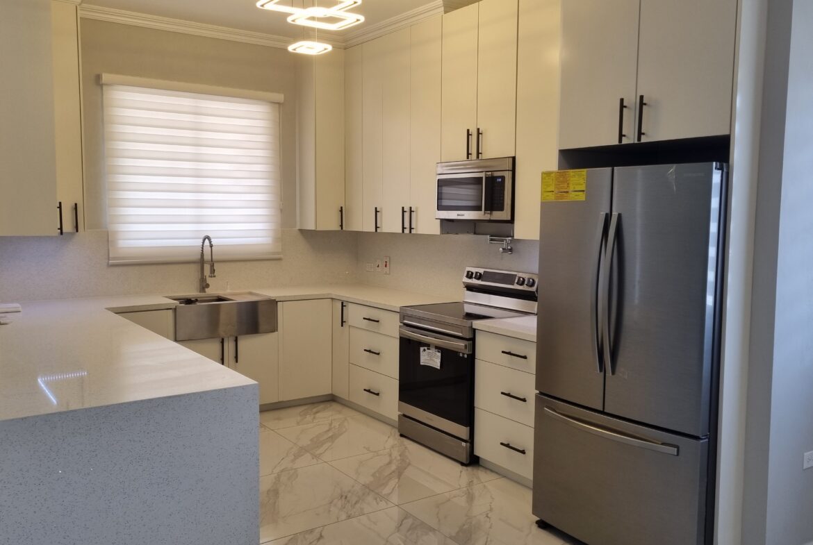 Modern kitchen with stainless steel appliances, white cabinets, and granite countertops in a Freeport home.