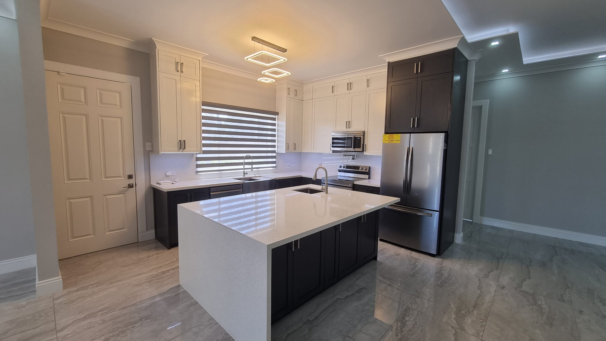 Modern kitchen island with built-in sink, cooktop, and vent hood in a Freeport home.