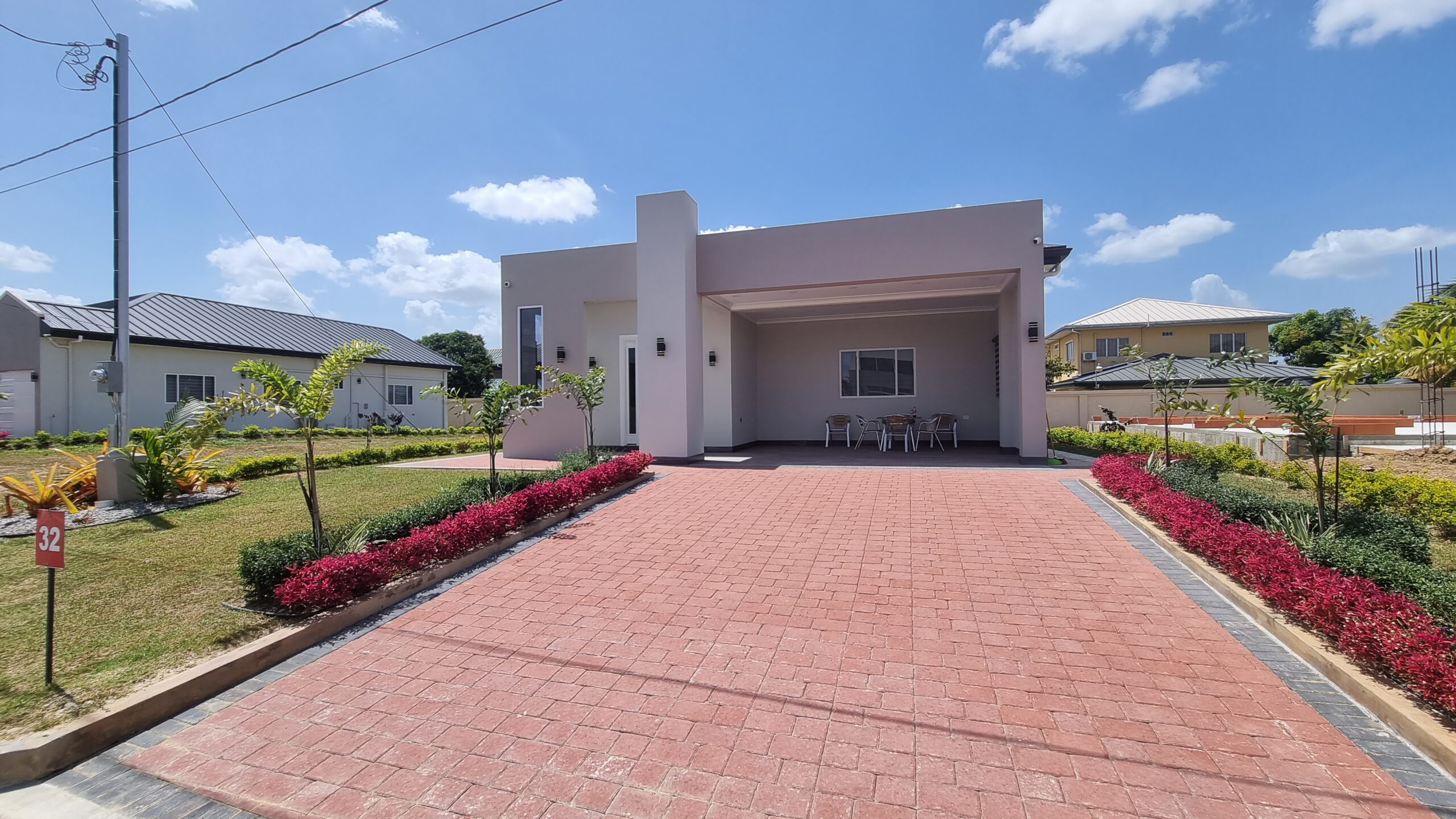 Modern Freeport home with red brick driveway and landscaped flower beds.