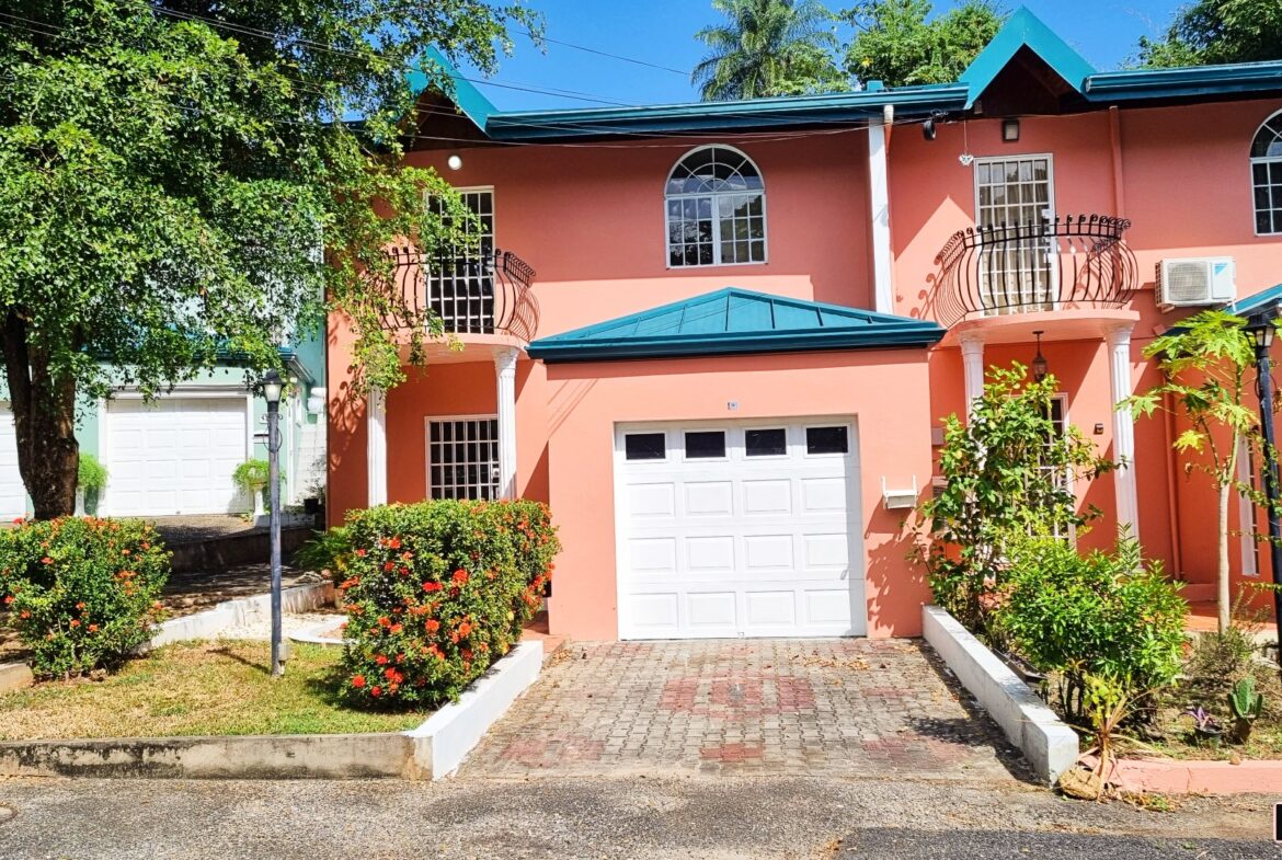 A pink three-bedroom townhouse with a white garage door.