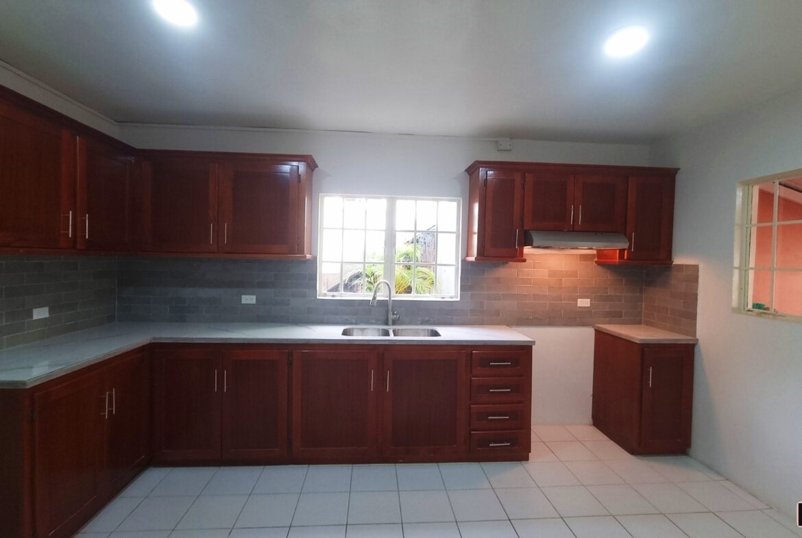 Kitchen with sink, cabinets, and window in a 3 bedroom townhouse rental.