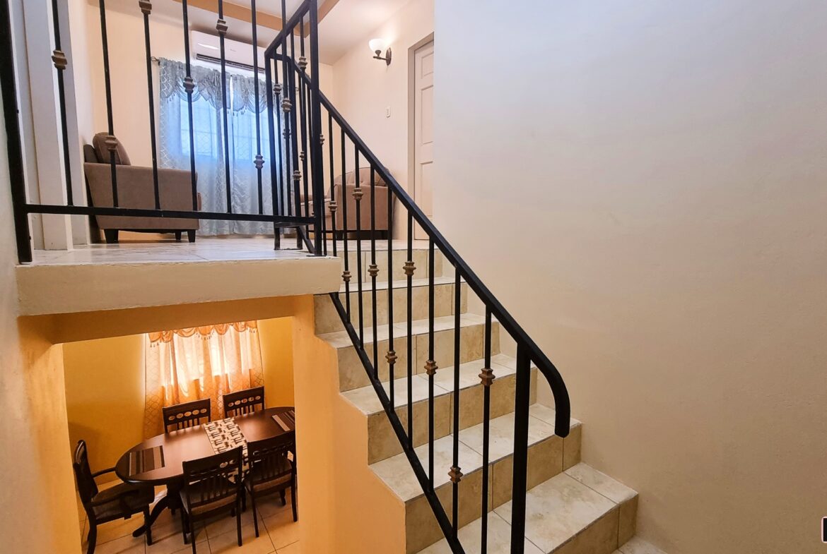 Staircase landing with two doors and a window in a townhouse for sale.