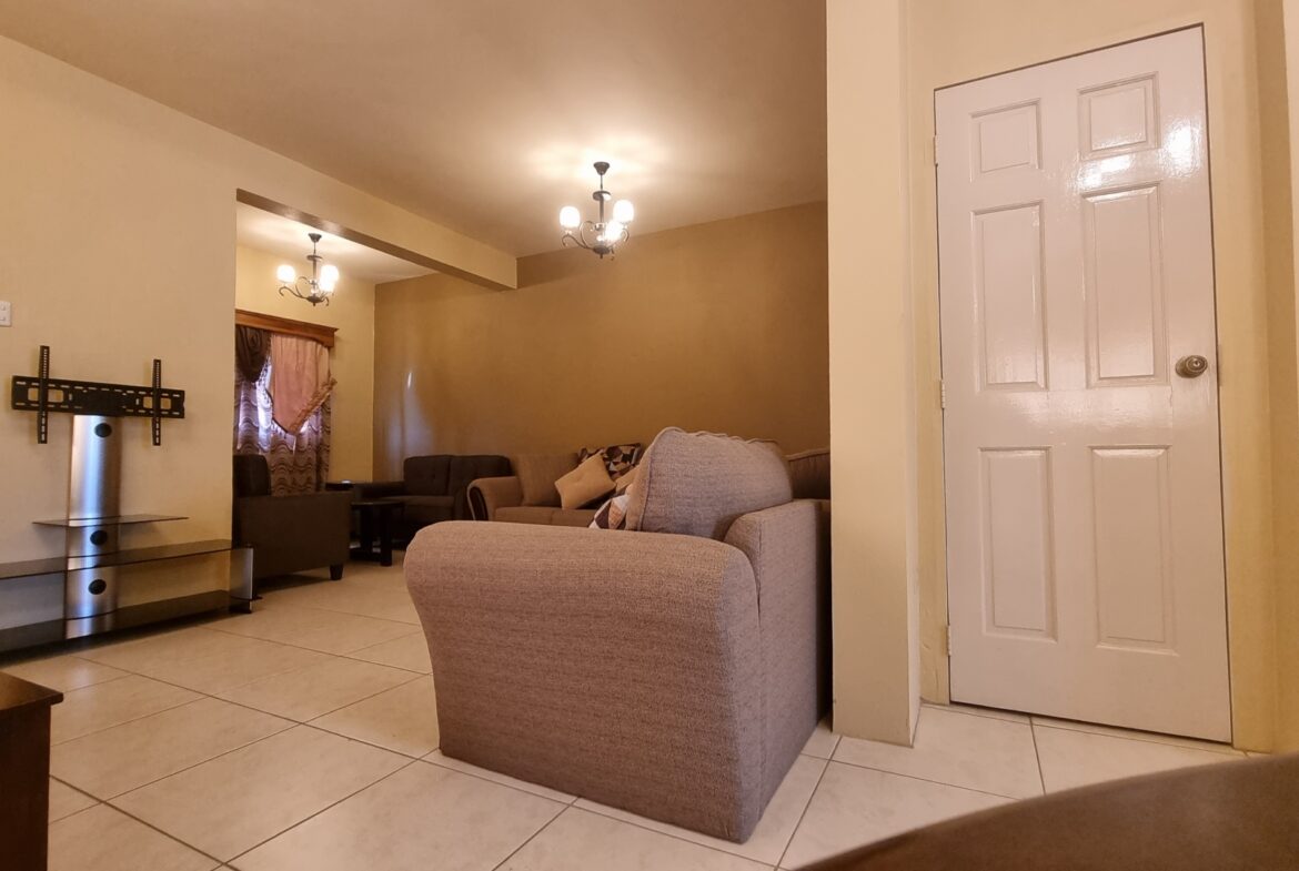 Living room area in townhouse for sale with couch, coffee table, and TV.
