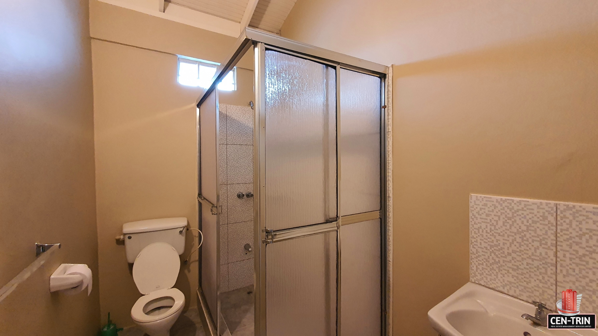 A charming bathroom with a toilet, shower with a glass door, and a sink with a mirror.