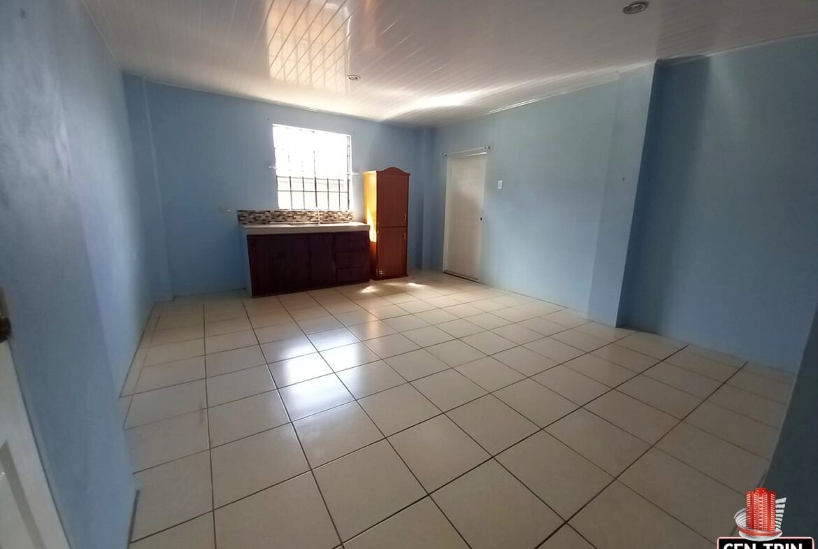 Interior of a kitchen with a refrigerator on the left and a sink on the right.