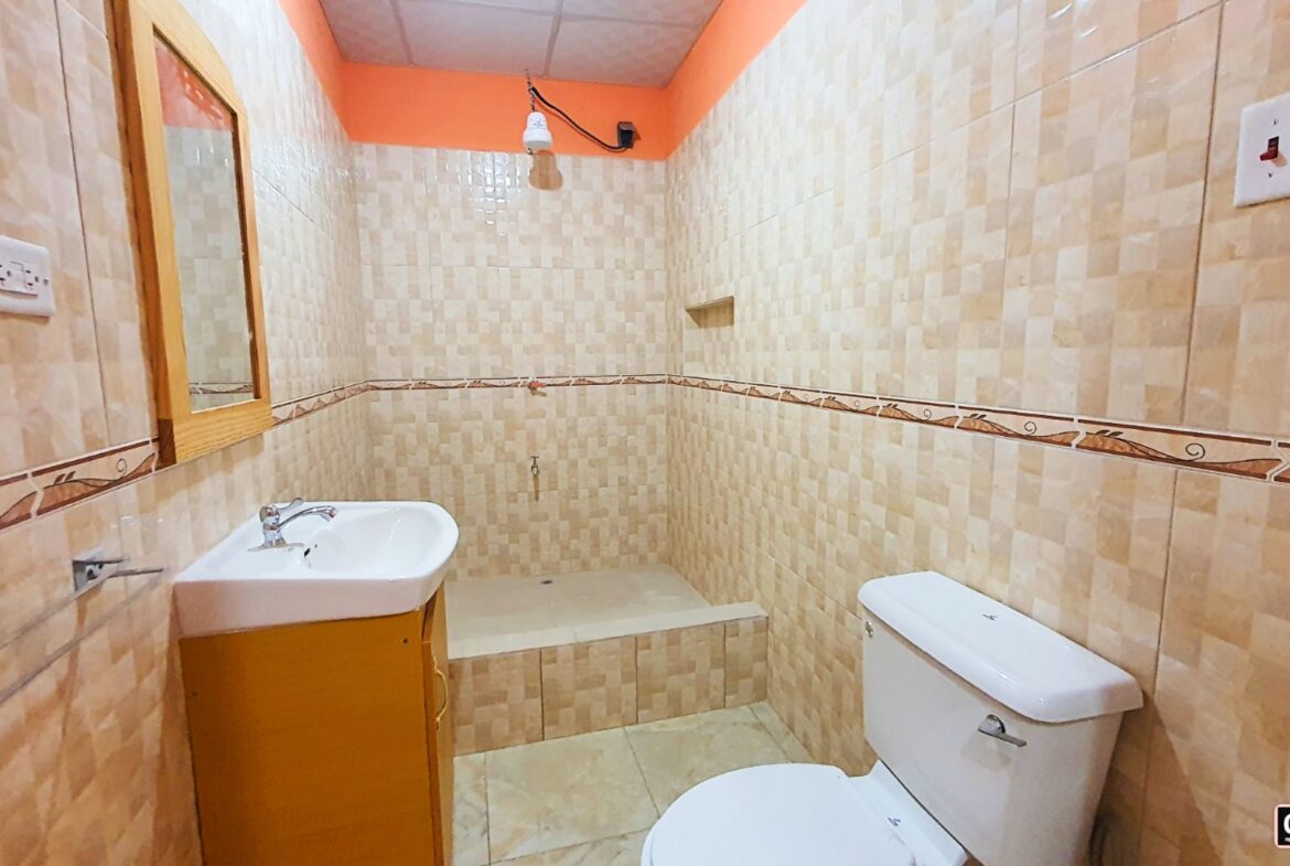 Bathroom interior with a toilet, sink with faucet, and a shower enclosure with a glass door.