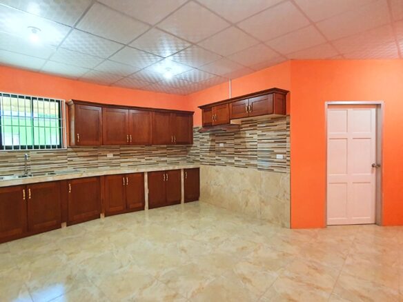 Kitchen with stainless steel sink and faucet, wooden cabinets, and orange walls in this 2-Bedroom Apartment for Rent