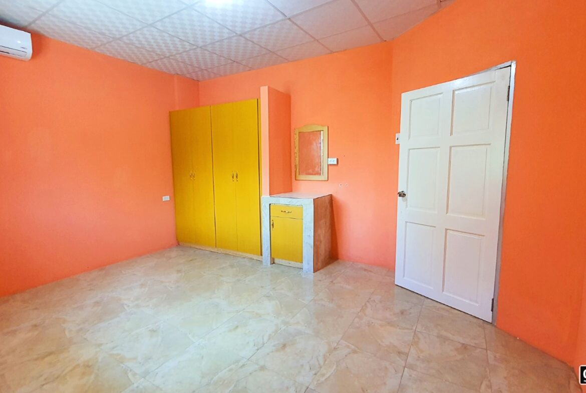 Bedroom interior with orange walls, a white wardrobe with mirrored doors, and a closed white door.