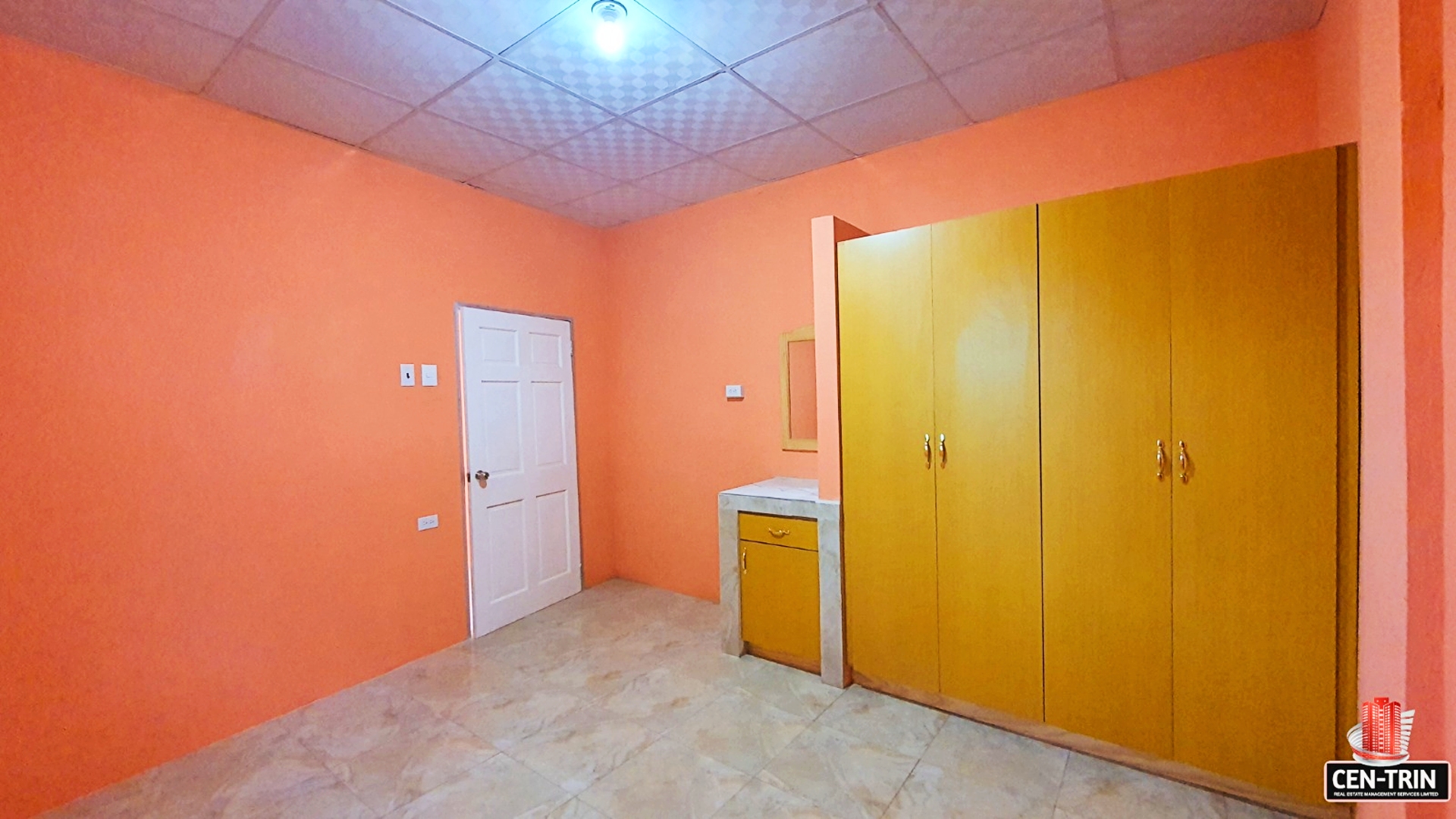 Interior of a bedroom with orange walls and wooden cabinets.