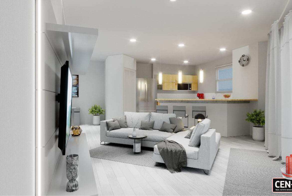 Living room interior with a couch, television, and kitchen visible in the background