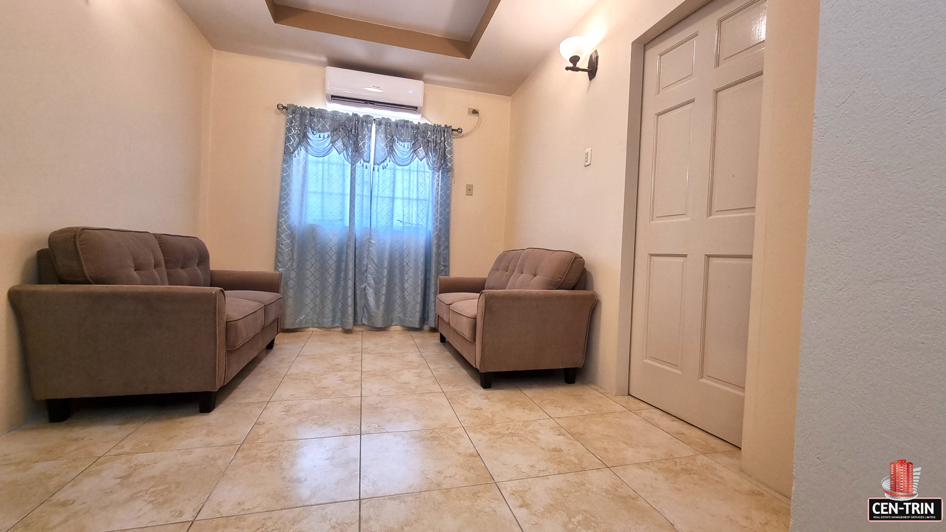 Upper sitting area in townhouse for sale with two couches, a window, and a door.