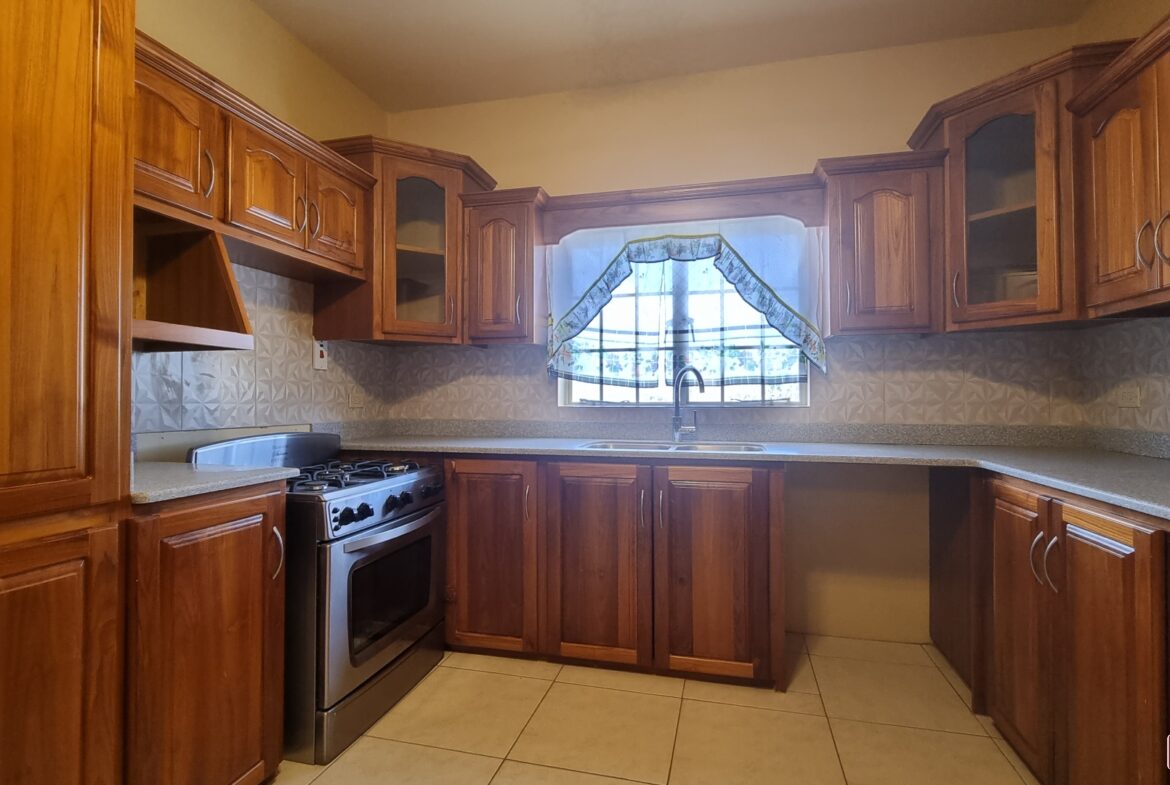 Kitchen with stove, sink, cabinets, and window in townhouse for sale.