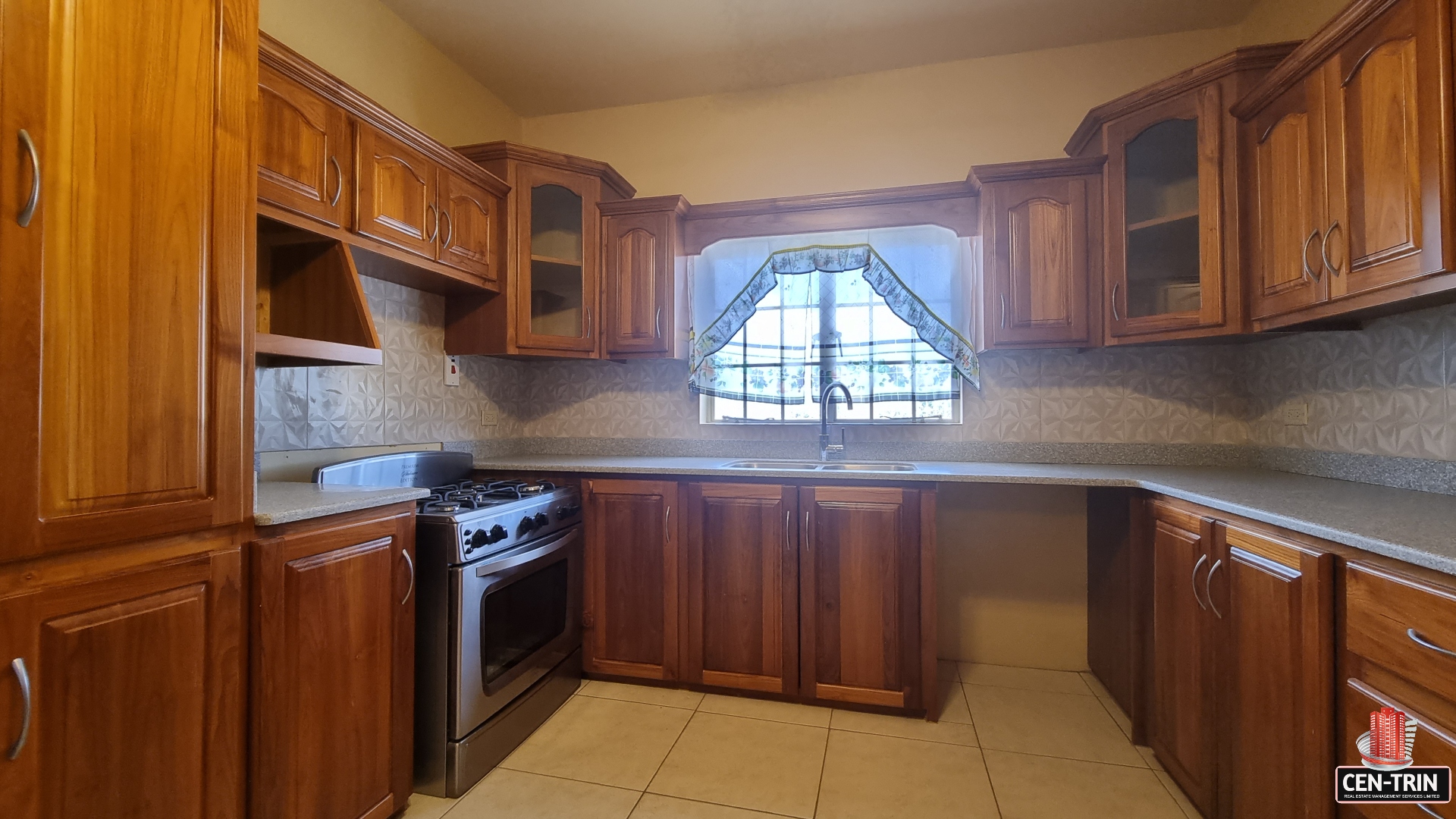 Kitchen with stove, sink, cabinets, and window in townhouse for sale.