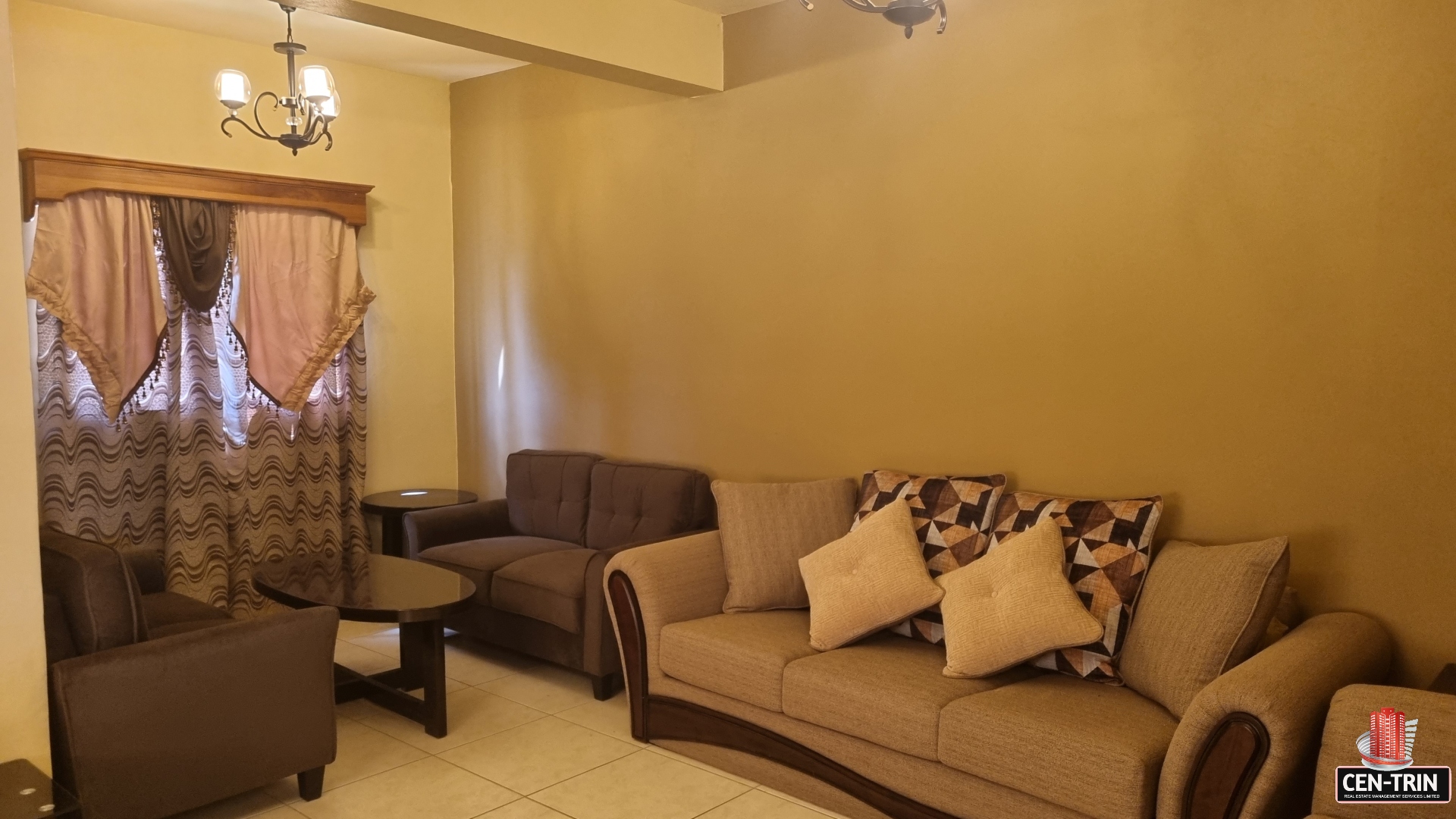 Living room in townhouse for sale with a couch, two armchairs, a coffee table, a fireplace, a TV mounted on the wall, and a large window.
