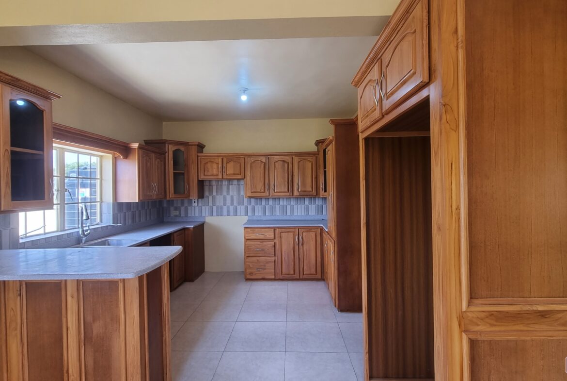 Kitchen area in townhouse for sale with wooden cabinets, sink, faucet, and stainless steel dishwasher.