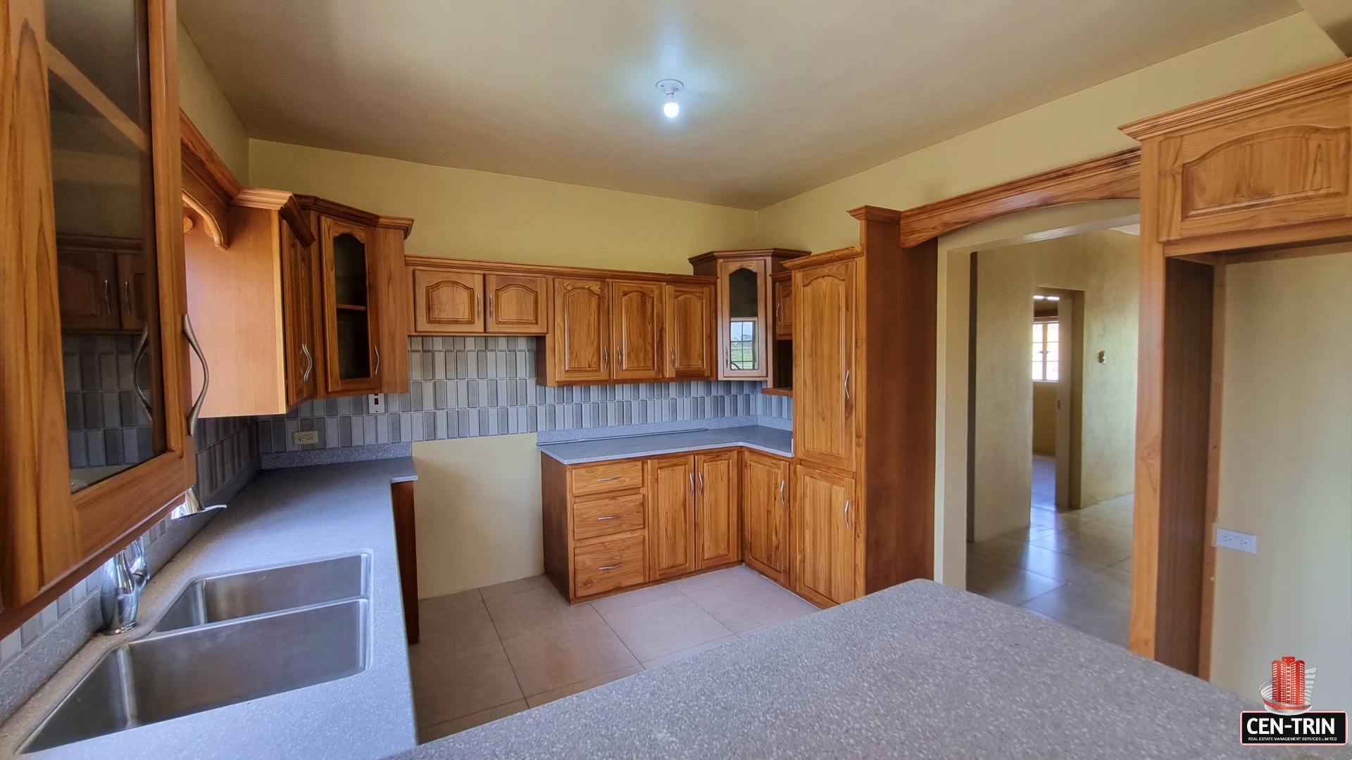 Kitchen with wooden cabinets, double sink, faucet, and granite countertops in townhouse for sale.