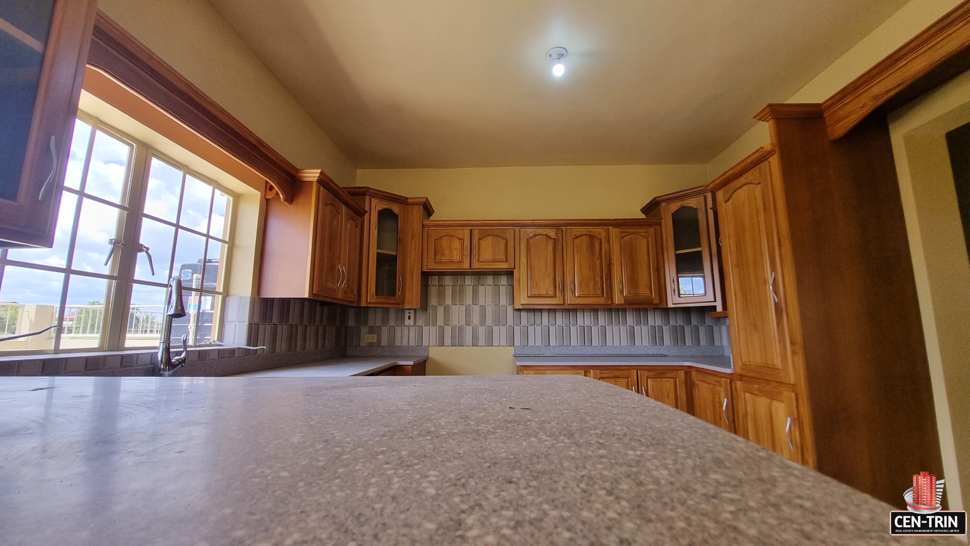 Modern kitchen with stainless steel appliances, sink, cabinets, and window in townhouse for sale.
