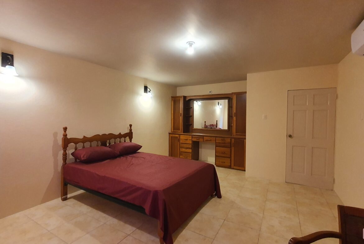 Master bedroom in townhouse for sale with bed, dresser, and mirror.