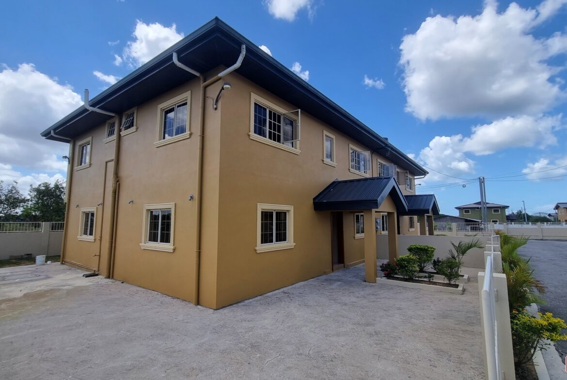 Large yellow townhouse with many windows for sale in a rural area.