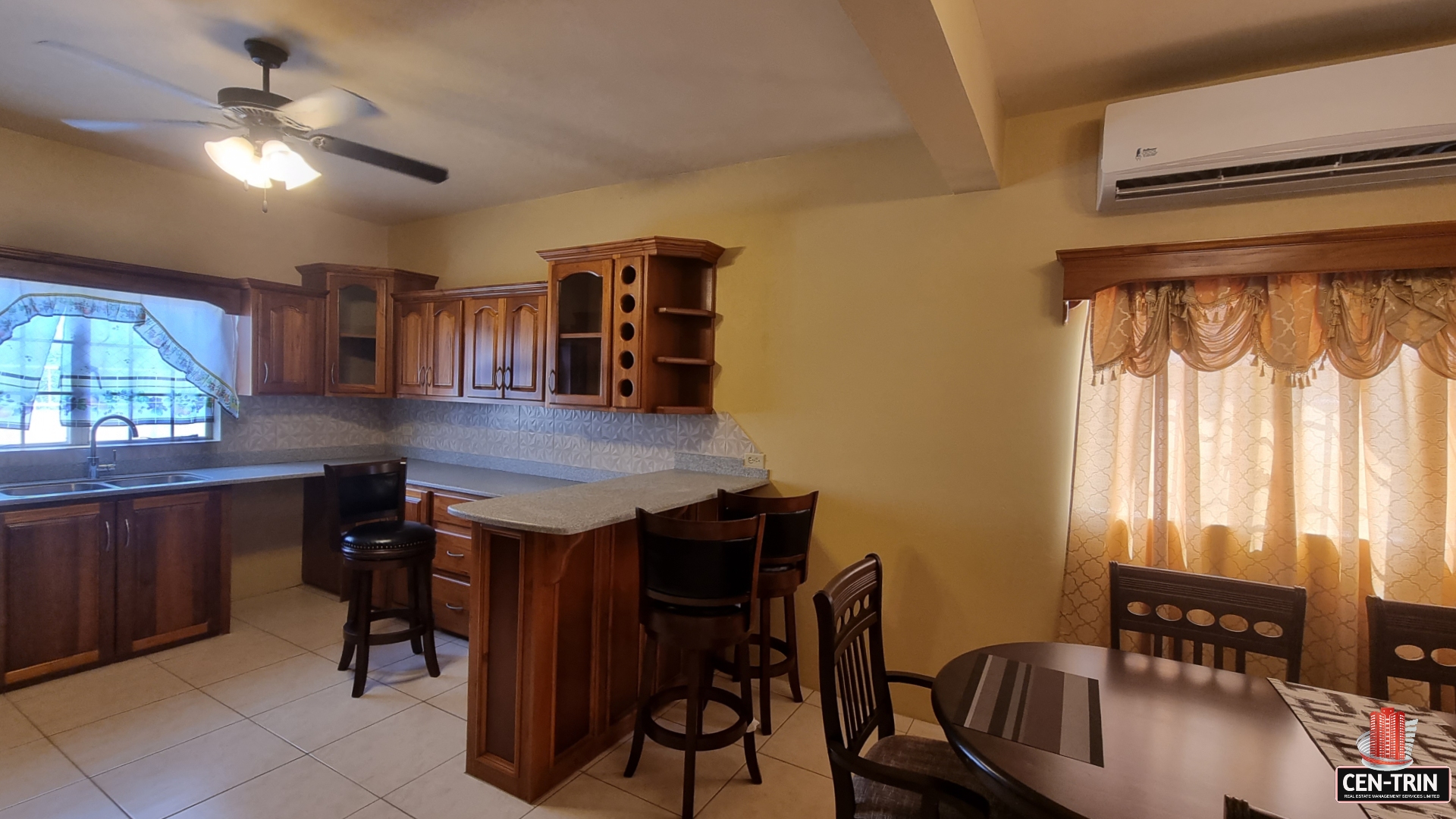 Kitchen area in townhouse for sale with wooden cabinets, sink, faucet, granite countertops, and stainless steel appliances. There is a window with a view of the backyard.