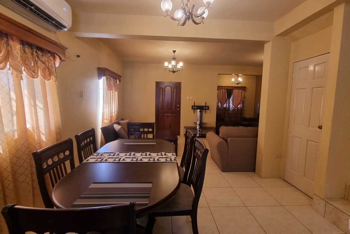 Living room area in townhouse for sale with a couch, coffee table, side table, and a large window.