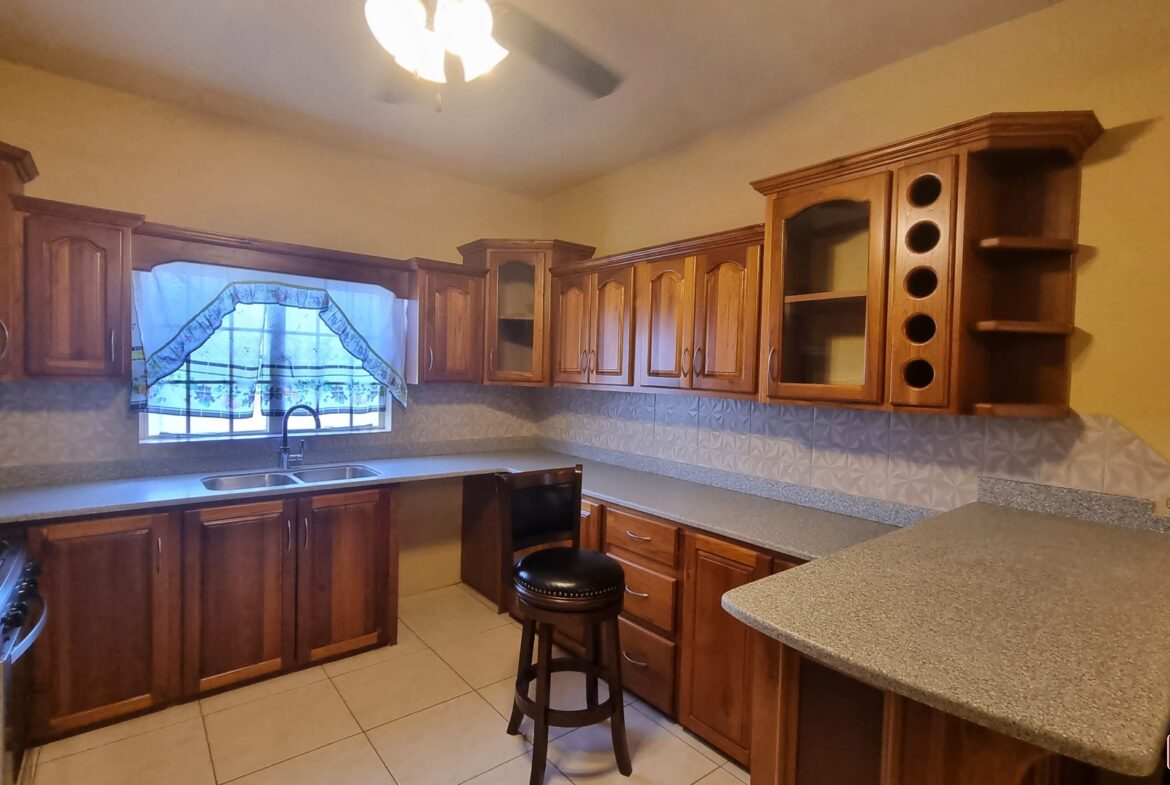 Modern kitchen area in townhouse for sale with stainless steel appliances, granite countertops, breakfast bar, and pendant lights.