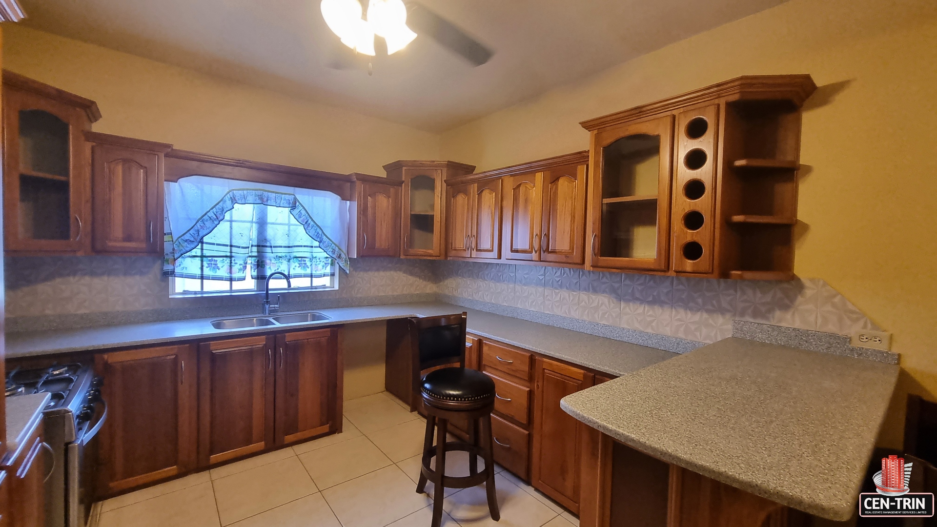 Modern kitchen area in townhouse for sale with stainless steel appliances, granite countertops, breakfast bar, and pendant lights.
