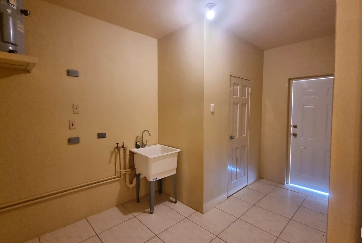 Laundry room in townhouse for sale with sink, faucet, cabinets, and washer and dryer.