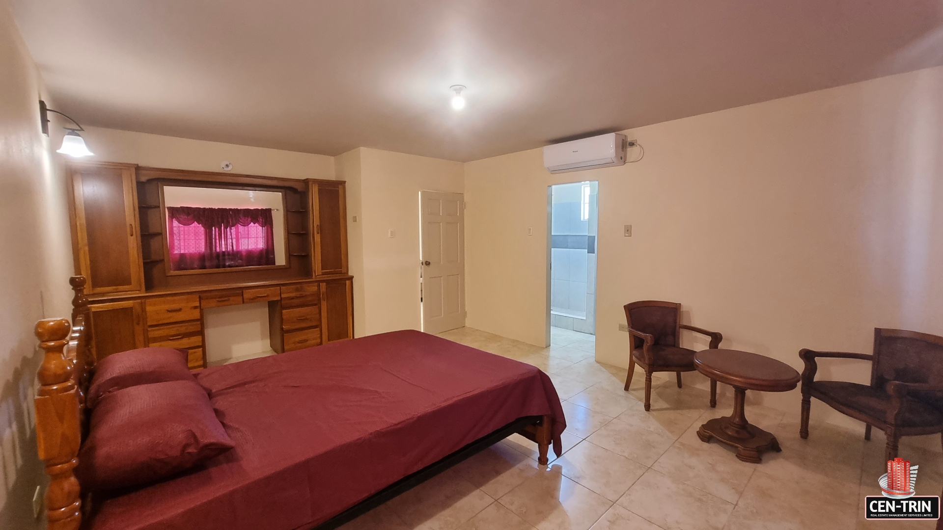Master bedroom in townhouse for sale with a king-size bed, two bedside tables with lamps, a dresser with mirror, and a window.