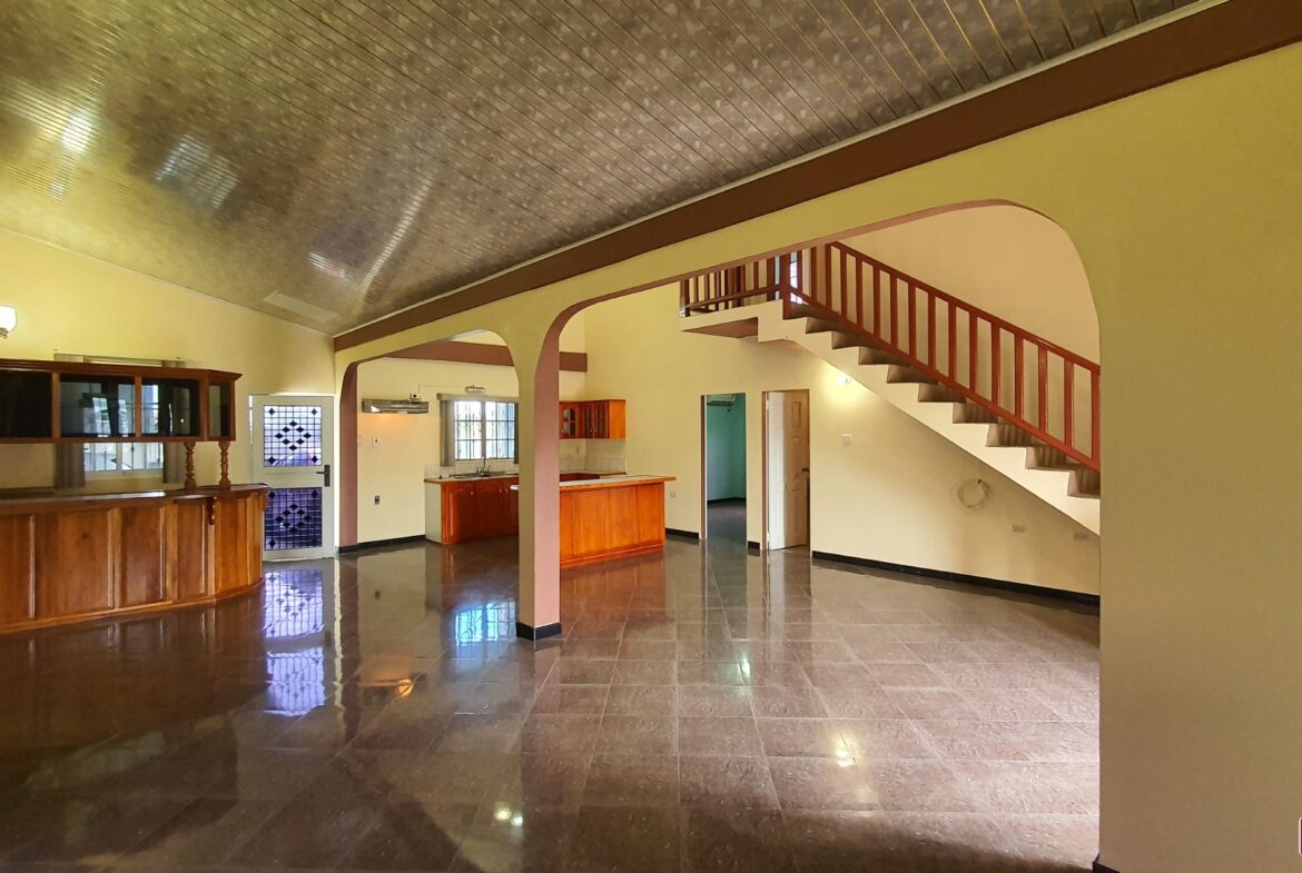 A charming room interior with a grand staircase leading to a second floor landing.
