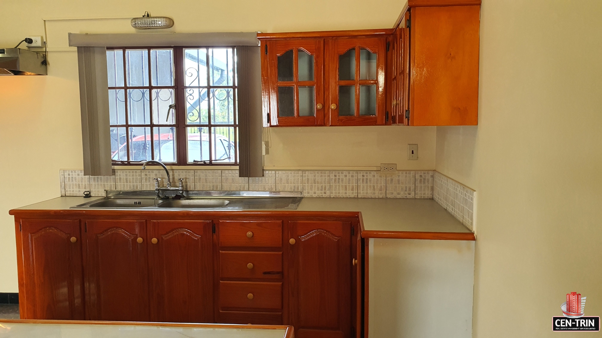 A charming kitchen with a farmhouse sink, white cabinets, and a window with a plant on the sill.