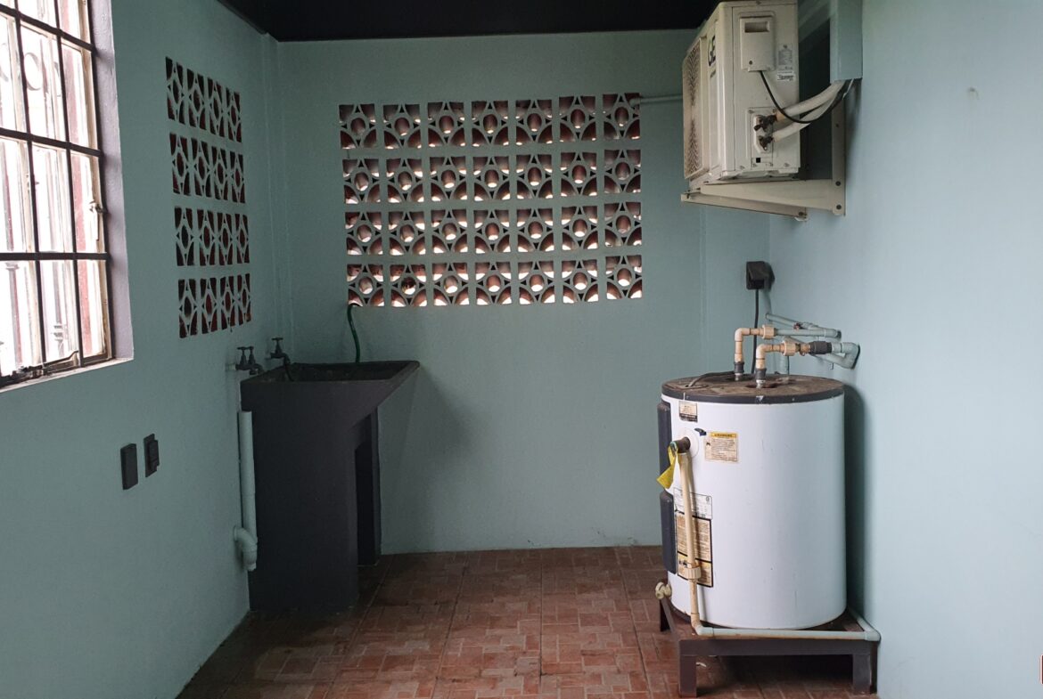 An outdoor laundry room with a sink, water heater, and air conditioner.
