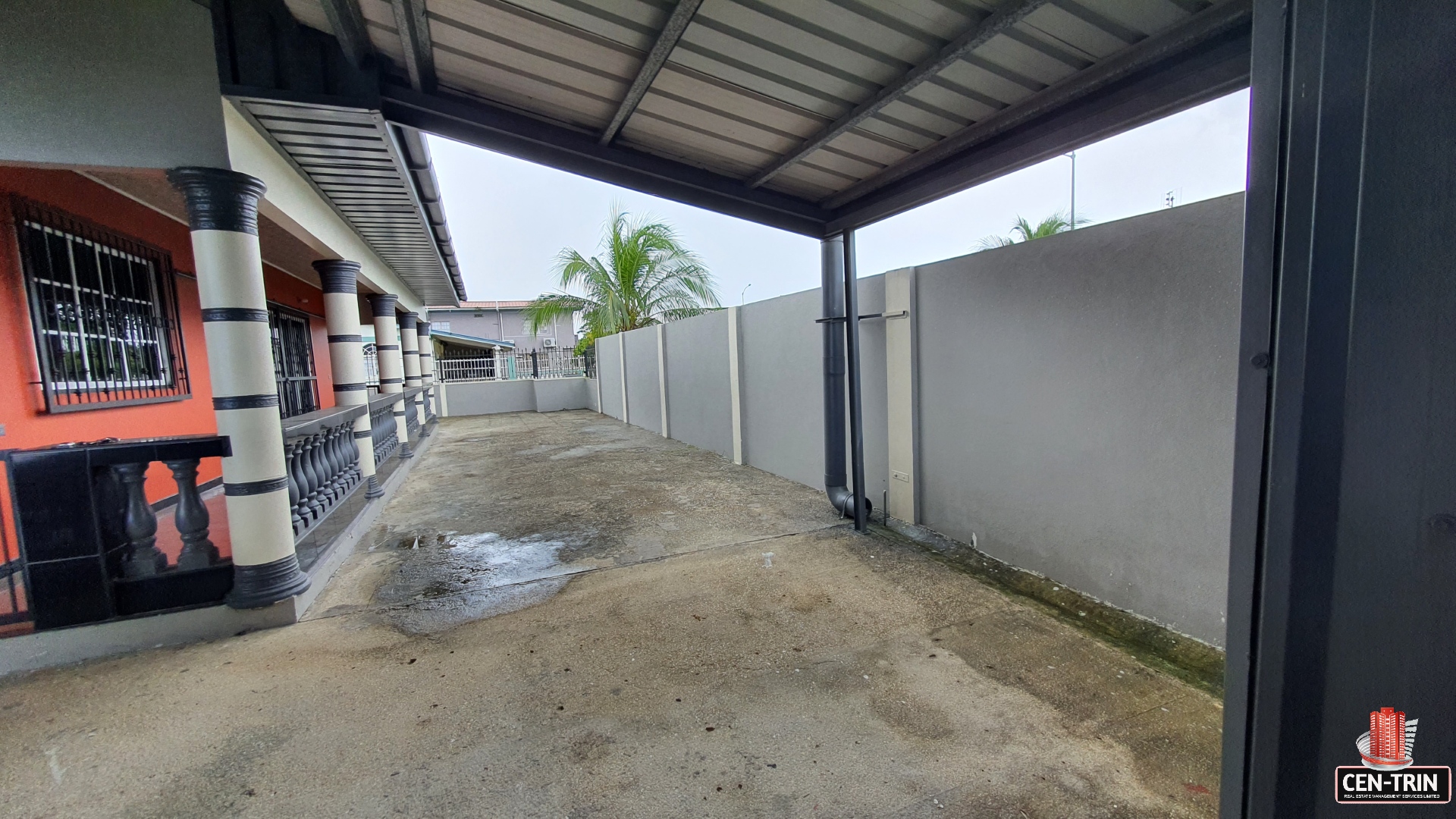 A house exterior with a covered driveway and a wall.
