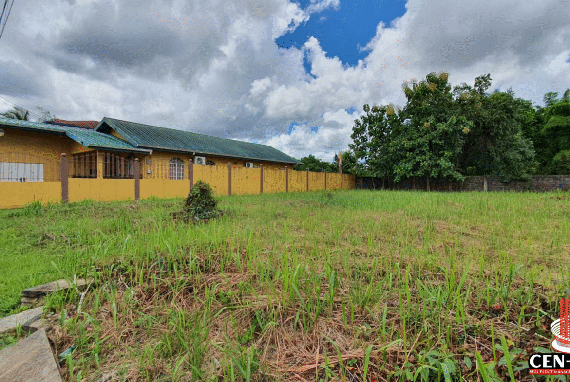 A clear, grassy, and level plot of land for sale in Trinidad, located in Krystal Gardens, Freeport, suitable for building a home. The image shows the dimensions of the lot (5011 sq. ft), and the surrounding partially built up area.