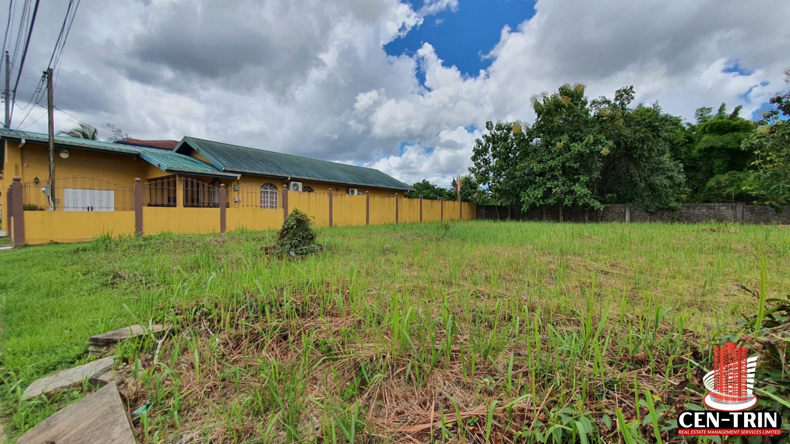 A clear, grassy, and level plot of land for sale in Trinidad, located in Krystal Gardens, Freeport, suitable for building a home. The image shows the dimensions of the lot (5011 sq. ft), and the surrounding partially built up area.