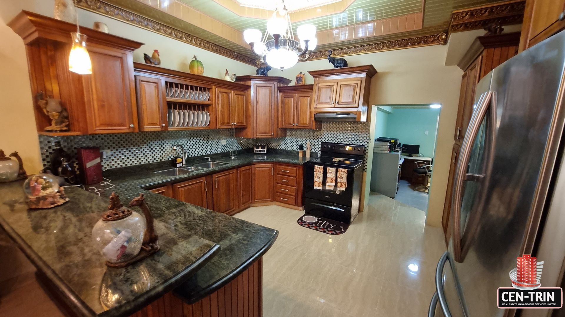 Spacious internal kitchen with elegant wooden cabinetry, granite countertops, and modern appliances in this luxury home for sale in Cunupia