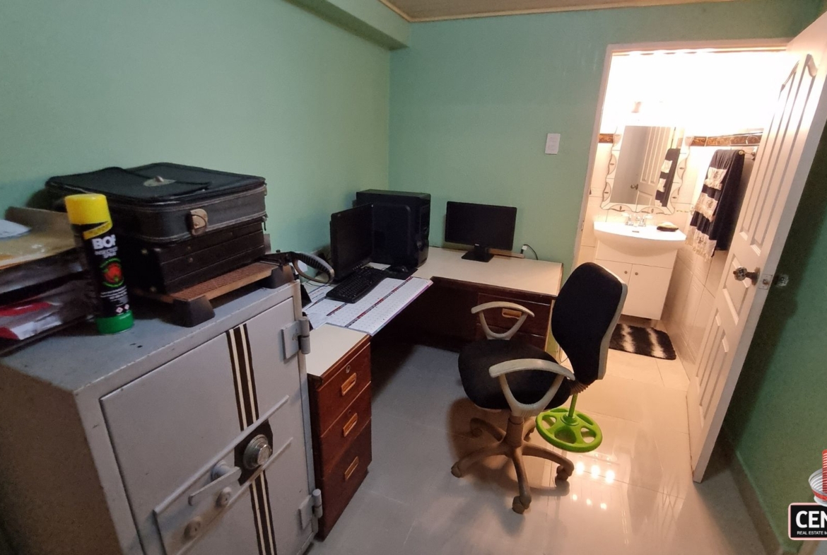 Functional home office space with computer setup and connecting en-suite bathroom in this luxury home for sale in Cunupia