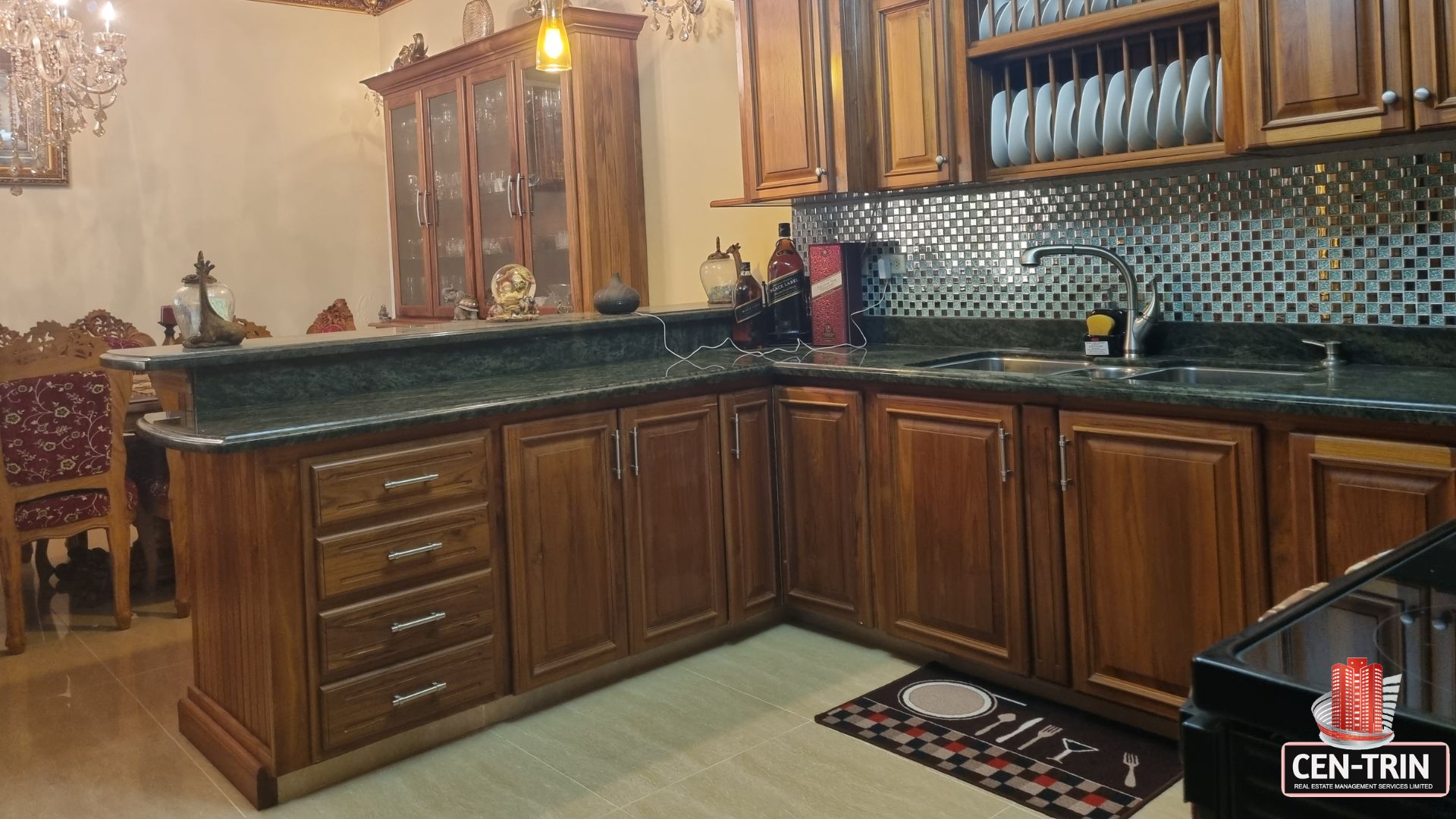 Close-up of the internal kitchen's wooden cabinets and dark granite countertops in this luxury home for sale in Cunupia