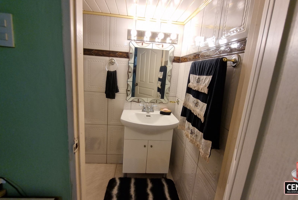 Clean and bright en-suite bathroom with vanity and tiled walls in this luxury home for sale in Cunupia