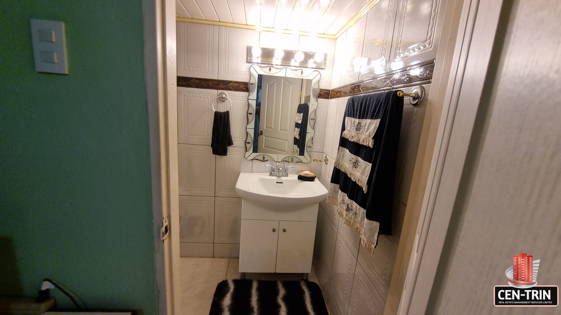 Clean and bright en-suite bathroom with vanity and tiled walls in this luxury home for sale in Cunupia