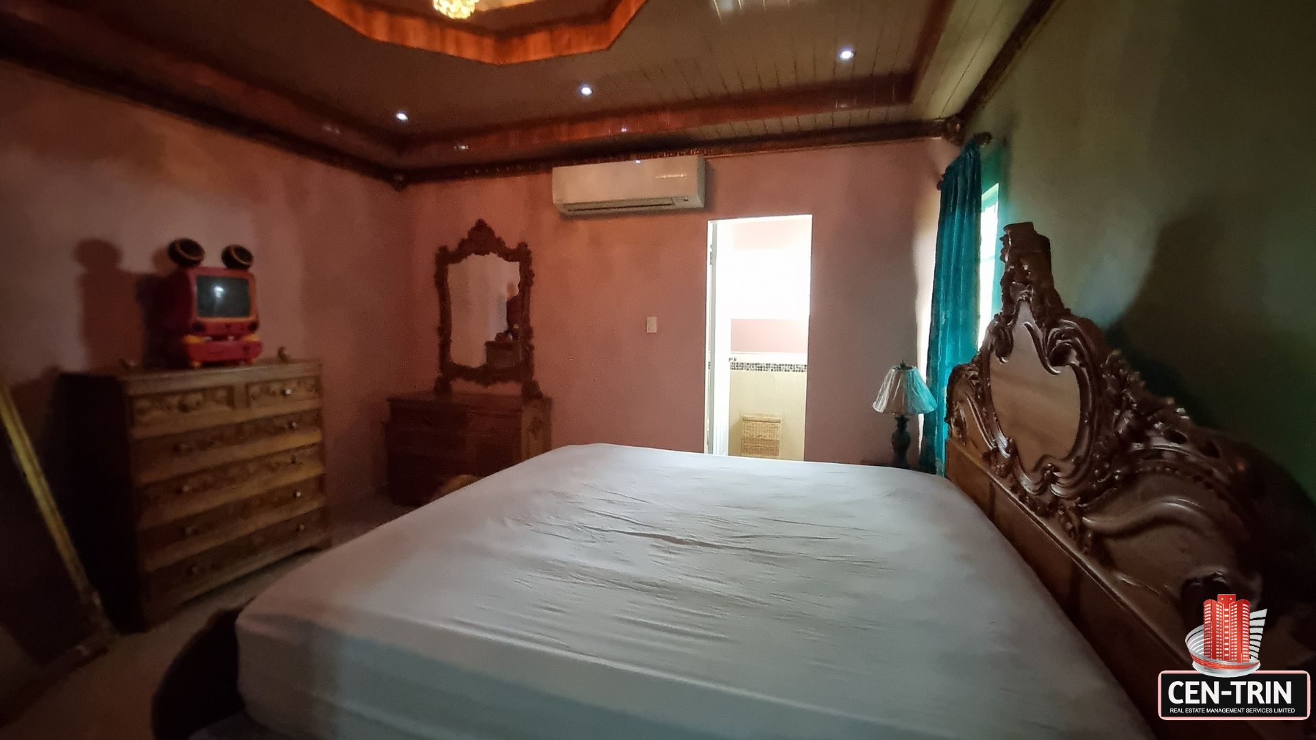 Beautifully furnished bedroom with carved wooden bed, dresser, and private en-suite bath in this luxury home for sale in Cunupia
