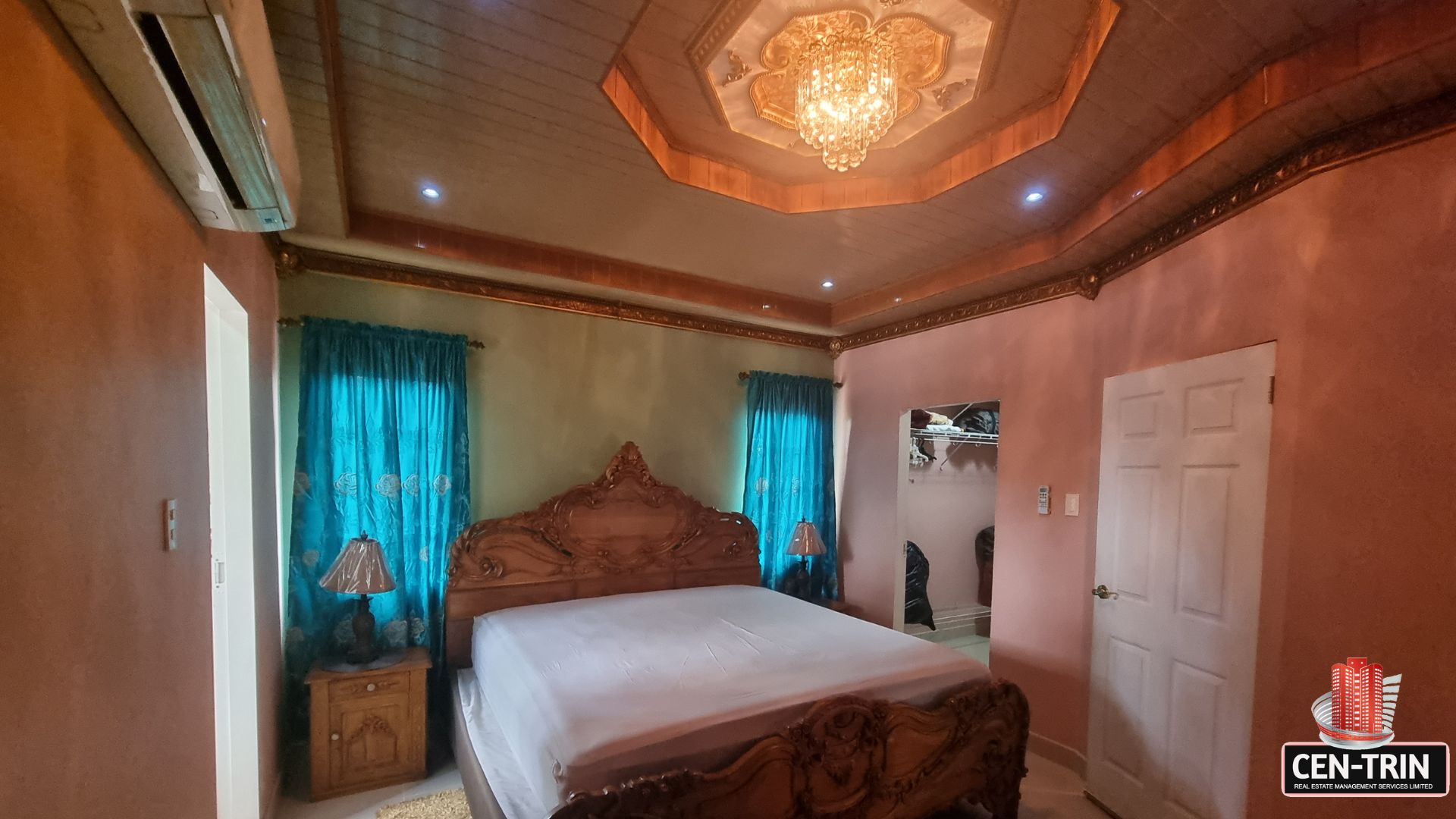Luxurious bedroom with carved bed, air conditioning, and access to a walk-in closet in this luxury home for sale in Cunupia