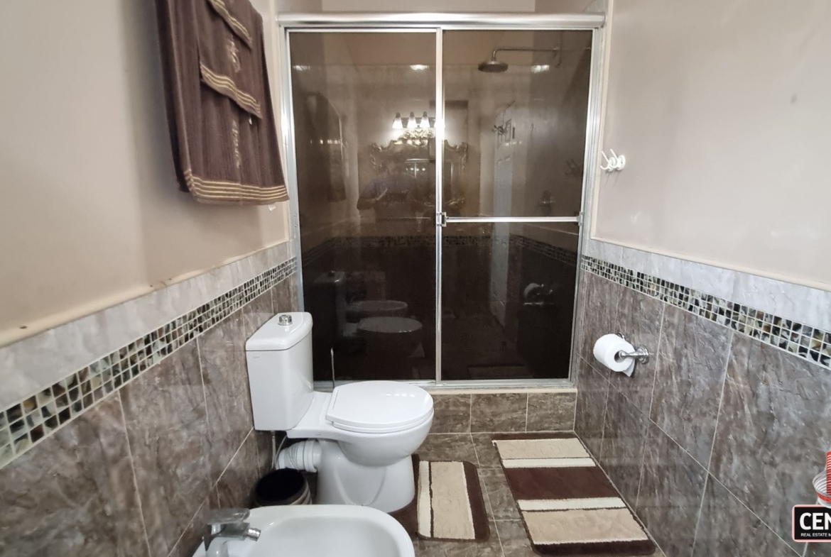 Modern en-suite bathroom with glass-enclosed shower, toilet, and bidet in this luxury home for sale in Cunupia