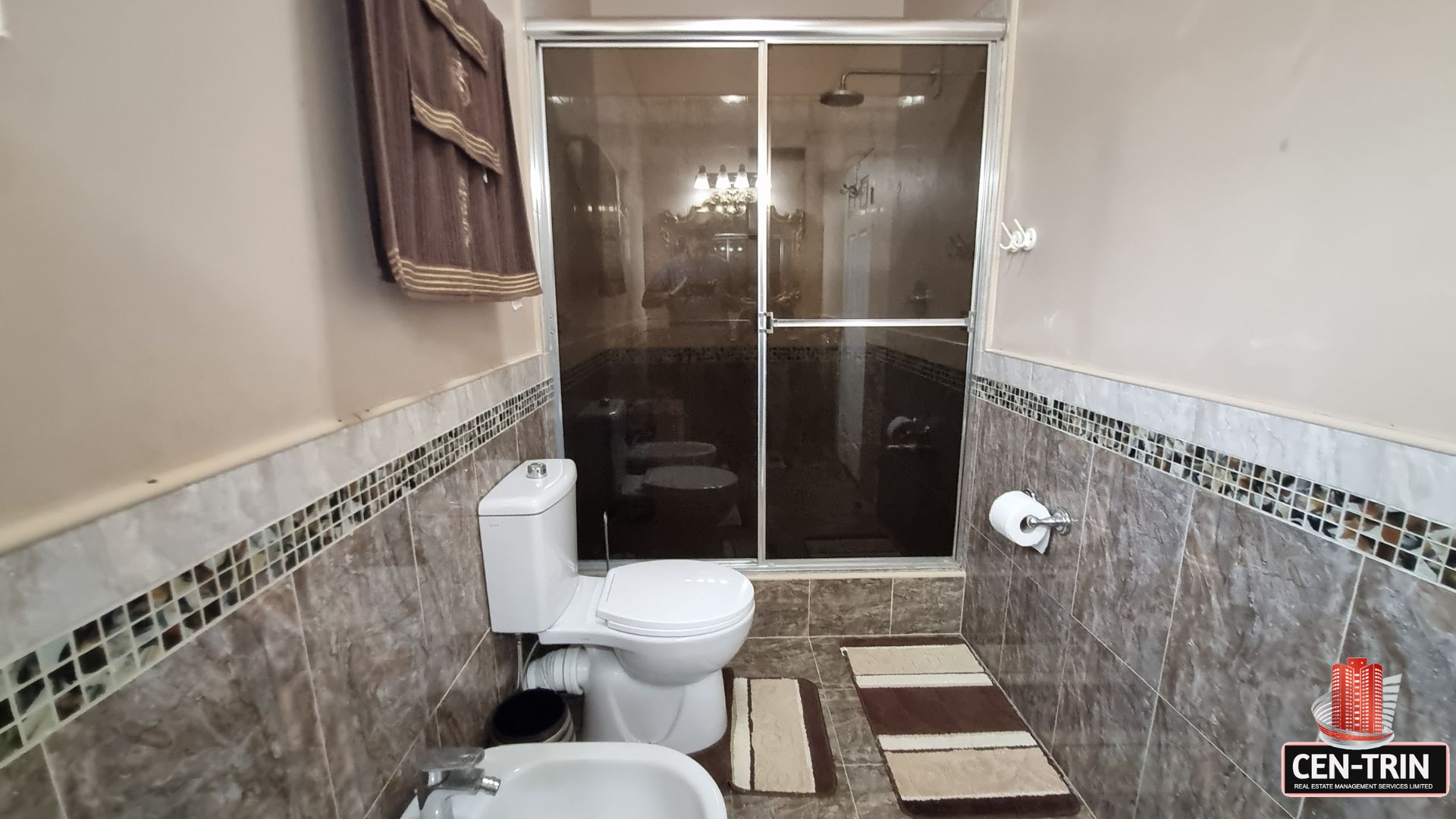 Modern en-suite bathroom with glass-enclosed shower, toilet, and bidet in this luxury home for sale in Cunupia