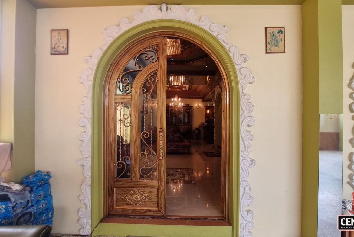 Ornate main entrance with carved wooden door and decorative archway of this luxury home for sale in Cunupia