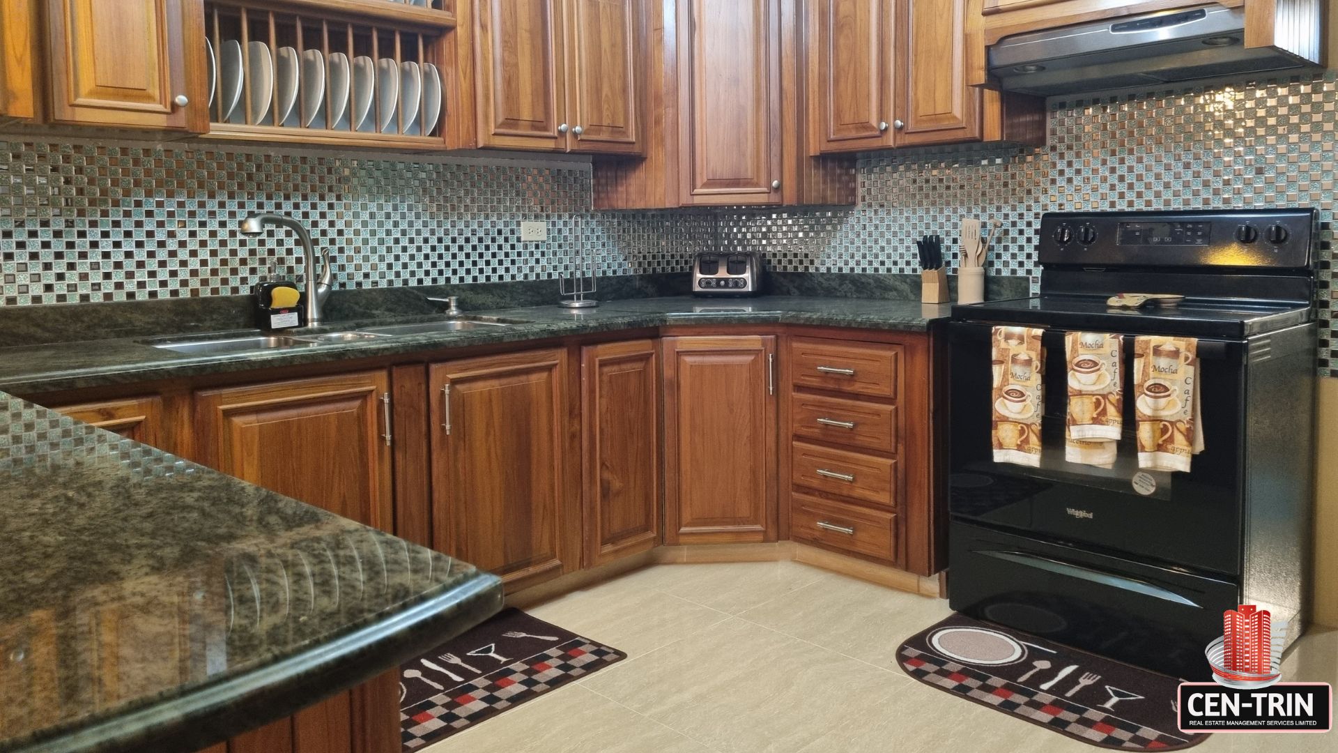 Well-appointed internal kitchen with wooden cabinets and mosaic tile backsplash in this luxury home for sale in Cunupia